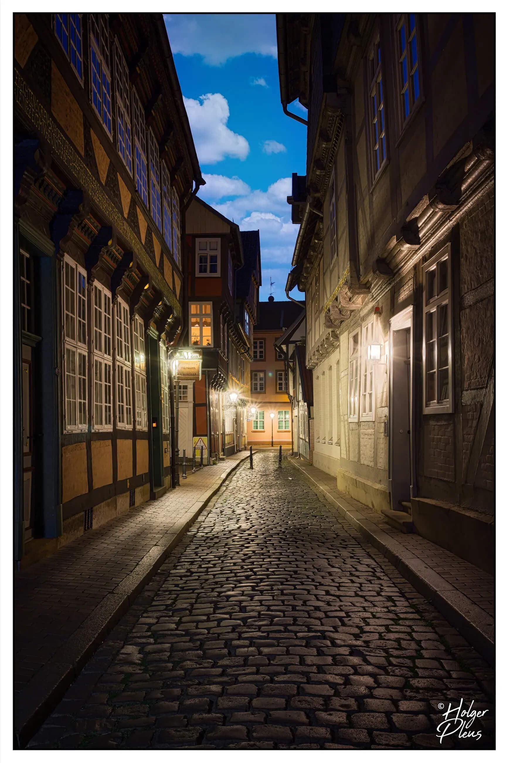 Nachtaufnahme einer kopfsteingepflasterten Straße mit einem Sommertags-Himmel darüber